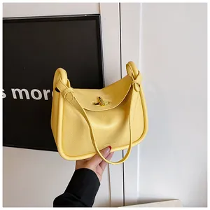 Detailed shot of yellow leather handbag with knotted handle and metal twist lock closure