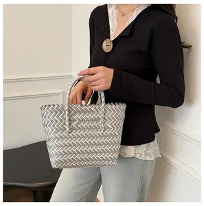 Détail du sac cabas tressé à carreaux gris et blanc montrant la texture et l'anse