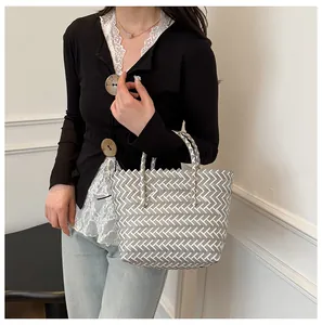 Détail du tissage géométrique en V sur un sac seau en paille tressée gris et blanc