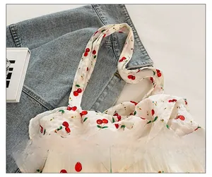 Détail de la large bandoulière avec imprimé cerises sur un sac fourre-tout en toile