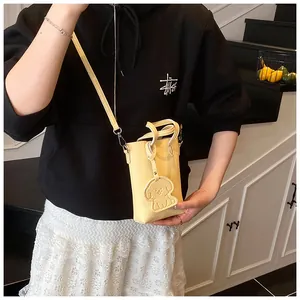 Dettaglio della mini borsa a tracolla gialla con trama litchi e ciondolo a forma di cane