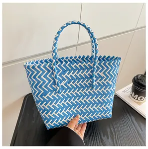Détail du tissage diagonal bleu et blanc sur ce sac cabas en paille élégant et moderne