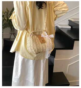 Detail of straw woven shoulder bag featuring a leather flap with gold buckle and lace bow