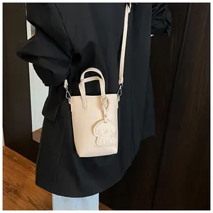 Dettaglio della mini borsa beige in pelle martellata con ciondolo a forma di cane