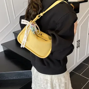 Bright yellow pebbled leather shoulder bag with decorative pearls and lace ribbon pendant