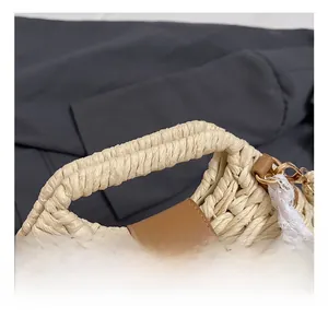 Detail of woven straw bag handle with brown leather accents and white lace ribbon