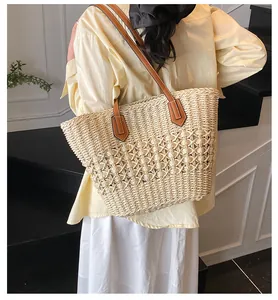 Detail of hand-woven straw tote bag with dual texture patterns and brown leather straps