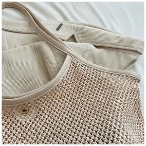 Detail of straw woven tote showing mesh texture, leather trim and gold metal fastener