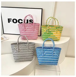 Détail de quatre sacs cabas tissés colorés avec motif à chevrons sur présentoir épuré