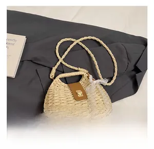 Detailed close-up of woven straw bag with brown leather flap and golden metal clasp lock