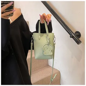 Dettaglio mini borsa tote verde chiaro in pelle martellata con tracolla e ciondolo cane