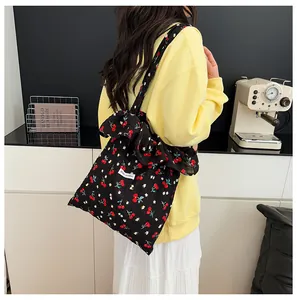 Détail du sac cabas floral noir avec imprimé cerise et décoration grand nœud papillon