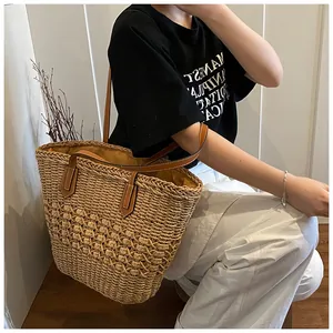 Detail of hand-woven straw tote bag featuring brown leather handles and natural texture