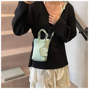 Dettaglio mini borsa verde chiaro in pelle martellata con un ciondolo a cane carino