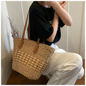 Close-up of hand-woven straw tote bag with brown leather strap and textured knit pattern