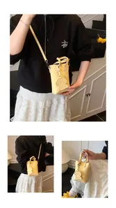 Dettaglio della mini borsa porta cellulare gialla con trama litchi e ciondolo a cane