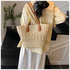 Detail of hand-woven straw tote bag with brown leather straps on a fashion model