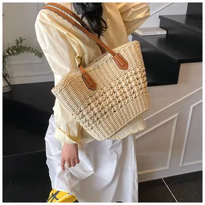 Detail view of woven straw tote bag with brown leather handles and hollowed-out texture