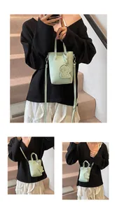 Dettaglio mini borsa verde menta in pelle martellata con ciondolo a cane e tracolla