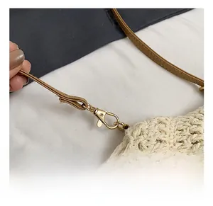 Détail du fermoir mousqueton doré et de la bandoulière en cuir du sac tissé chic