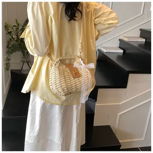 Detail of straw woven crossbody bag with brown leather clasp and lace bow decoration