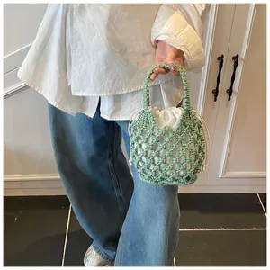 Sac seau en tricot vert tissé main avec doublure blanche tenu par un mannequin