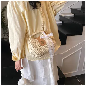 Close-up of a woven straw bag with a leather flap and delicate lace bow detail