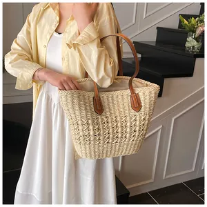 Detail of hand-woven straw tote bag with brown PU leather handles for beach vacation