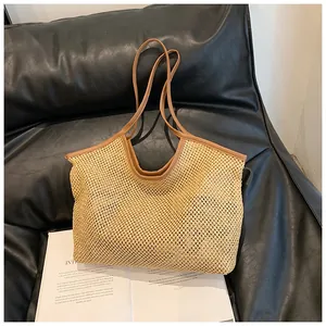 Close-up of fine mesh weave texture and brown leather strap on large straw beach tote bag