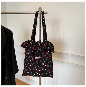 Détail du sac cabas floral avec imprimé cerises, bords volantés et étiquette Magic pocket