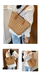 Close-up of woven straw tote bag with brown leather straps and hollow knit patterns