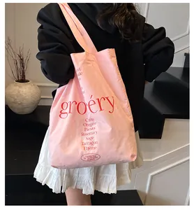 Vista detallada del bolso tote de lona rosa con estampado gráfico rojo y texto artístico