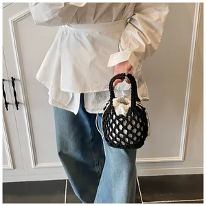 Détail d'un sac seau tissé noir avec une pochette blanche à cordon à l'intérieur