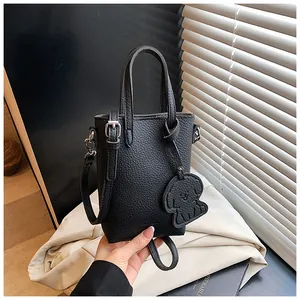 Dettaglio mini borsa nera a grana di litchi con ciondolo a forma di cane e dettagli argento