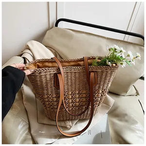 Detail shot of the woven straw texture and premium brown PU shoulder strap on this tote bag