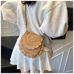 Détail du sac bandoulière en paille tressée avec texture et lanière en cuir brun