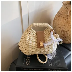 Detail of a straw beach bag with brown leather flap, metal lock and lace bow decoration