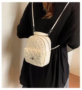 Detail of cream quilted mini backpack with rhinestone studs and chain shoulder straps