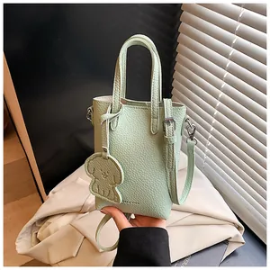 Dettaglio mini borsa a tracolla verde menta in pelle martellata con ciondolo cane