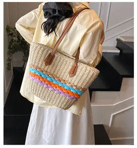 Vista posteriore dettagliata della grande borsa tote in paglia a righe colorate su una modella