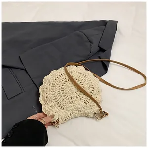 Détail du sac à bandoulière rond tressé beige avec bords ondulés et cuir marron