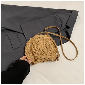 Détail du sac bandoulière rond en paille tressée avec bords festonnés et cuir
