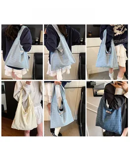 Detail view of large striped canvas tote bags in light blue and cream with wide shoulder straps