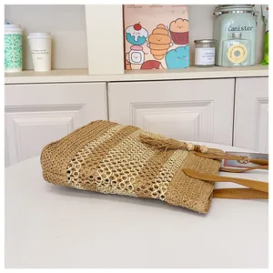 Detailed view of woven straw beach bag with leather handles and tassel accent