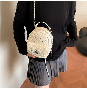 Detail of beige quilted backpack with rhinestone studs and silver metal chain strap