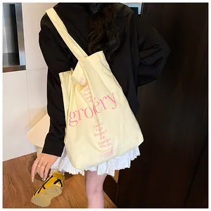 Detalle de bolso tote de lona amarillo claro con texto rosa y motivos de hierbas
