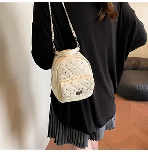 Detail of quilted beige mini backpack with crystal studs and silver twist lock on model