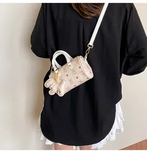 Close-up of cream Boston bag with bear monogram pattern and gold bear charm
