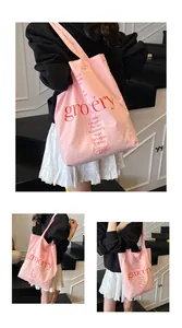 Detalle del bolso tote de lona rosa con texto rojo impreso y correa de hombro resistente