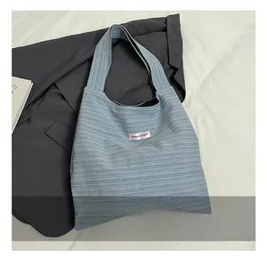 Close-up of blue striped canvas tote bag featuring a pink 'have a nice day' label